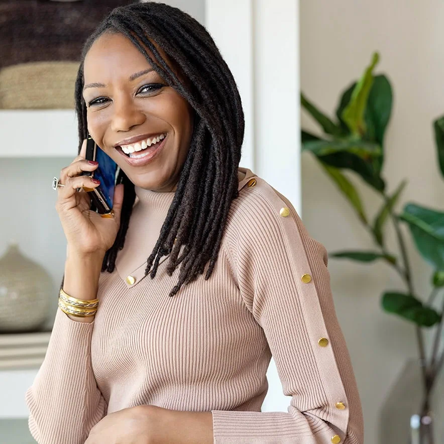 Dallas personal wardrobe stylist Roxanne Carne smiles at the camera while talking on a cell phone.
