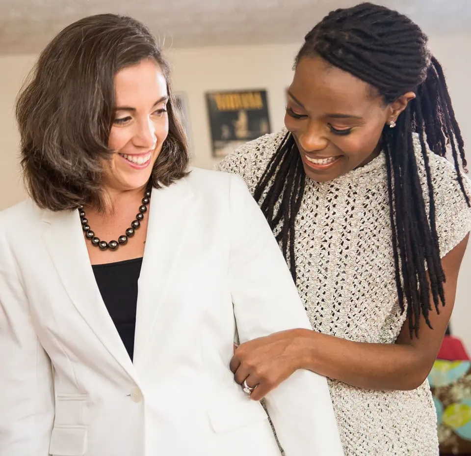 Roxanne helps a client into a white blazer during a closet makeover session.